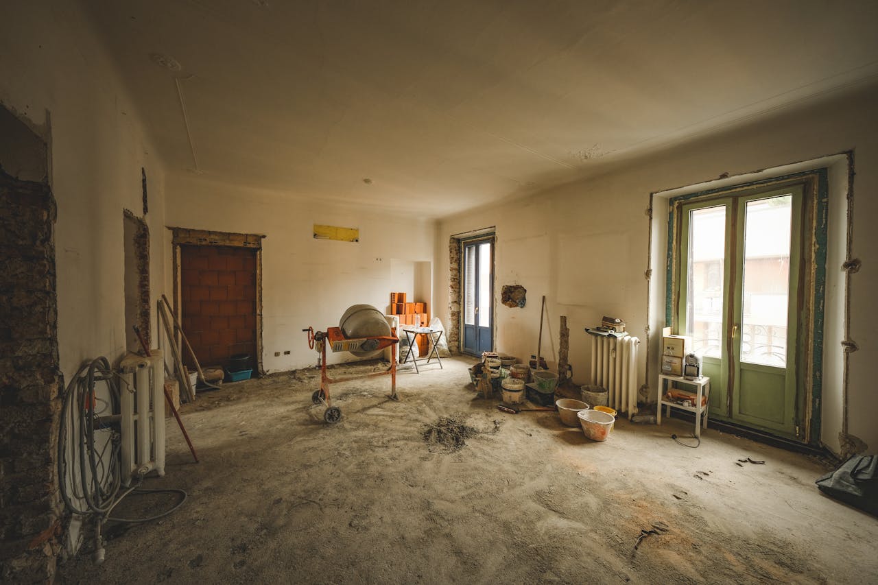 services-03 Wide view of a sunny room under renovation with construction materials and tools present, ideal for home improvement concepts.