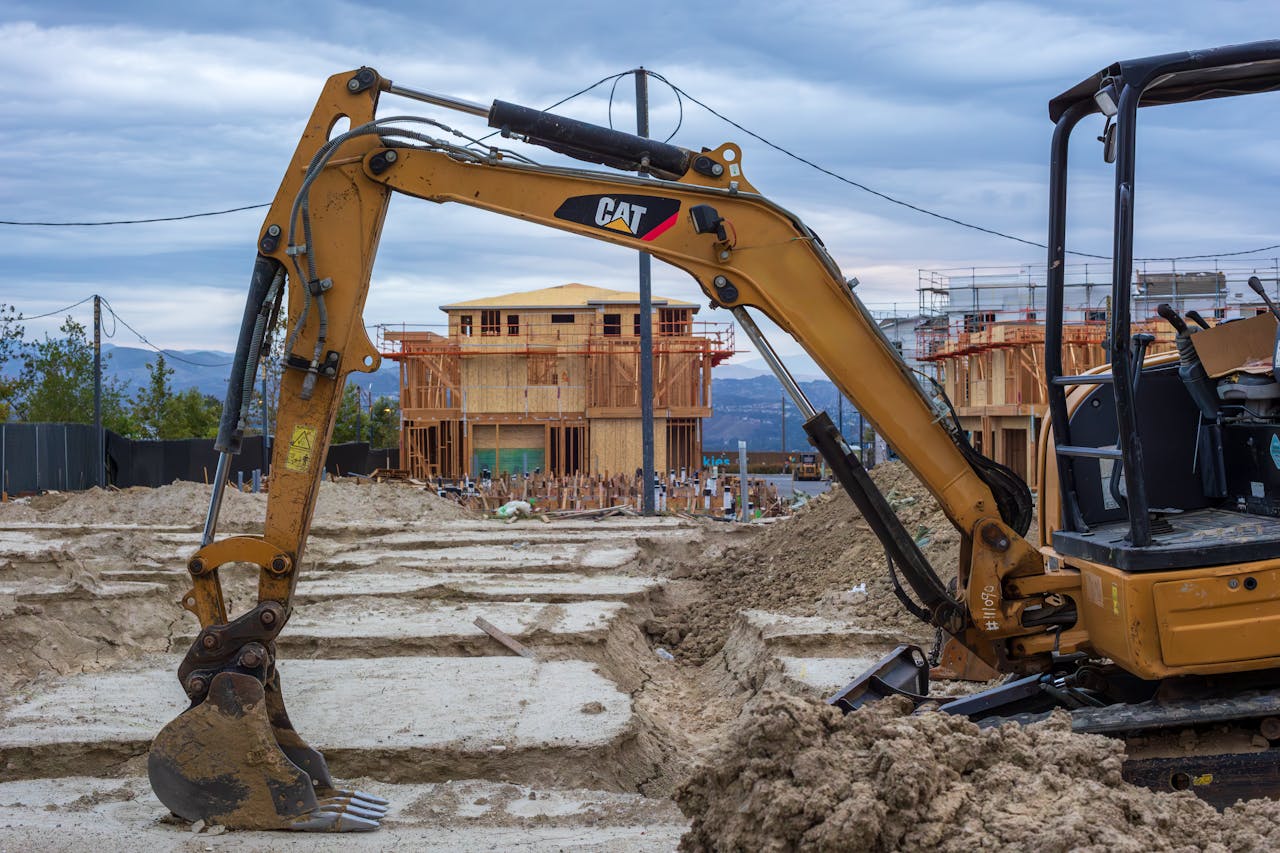 services-04 Excavator working on a new residential construction site with wooden frames.