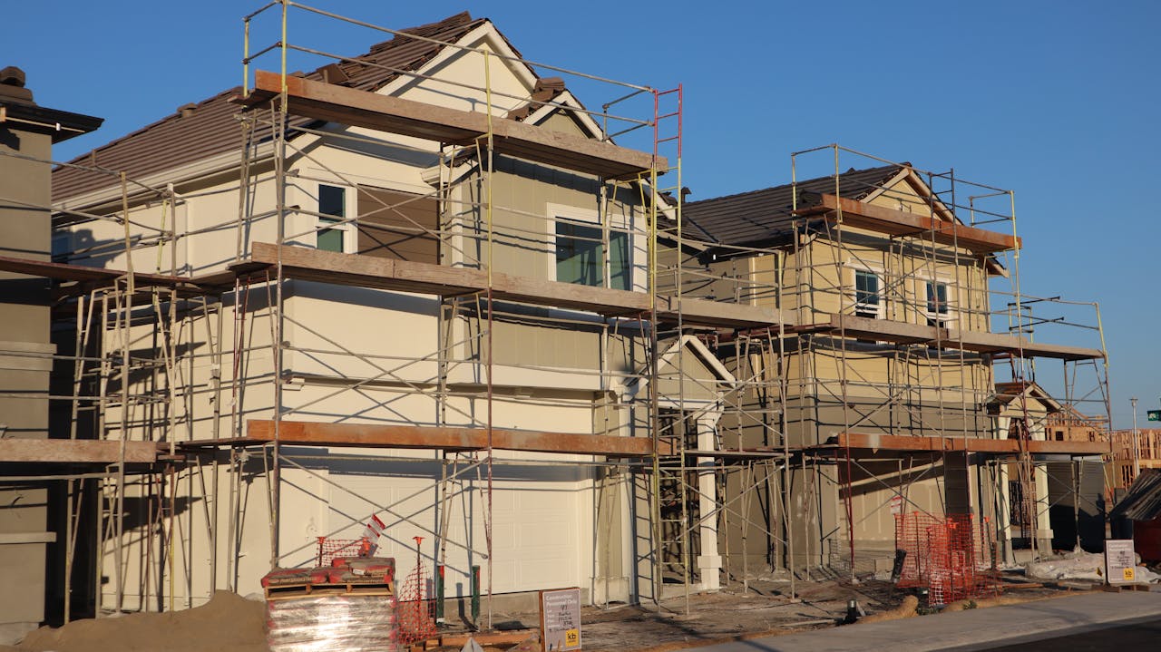 services-03 Scaffolded suburban homes under construction in Elk Grove, California during a sunny day.